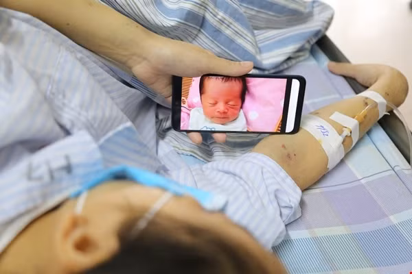 Chị Vang ngắn nhìn đứa con thơ qua màn hình điện thoại trong lúc điều trị. Chị Vang ngắn nhìn đứa con thơ qua màn hình điện thoại trong lúc điều trị.