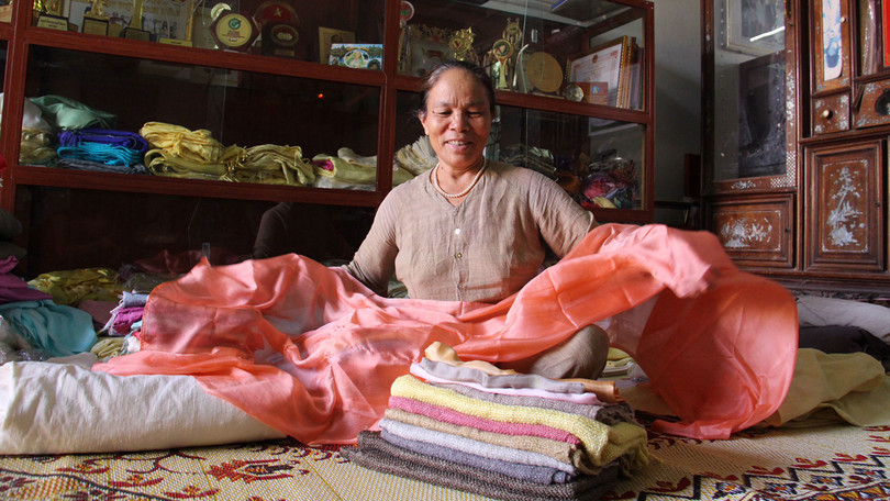 NNƯT Phan Thị Thuận và những thước lụa từ tơ tằm tại xưởng của bà. Với sự chăm chỉ, luôn mày mò sáng tạo bà đã nhận được rất nhiều bằng khen và giải thưởng trong nước về lĩnh vực tơ tằm. Ảnh: Thục Nhi