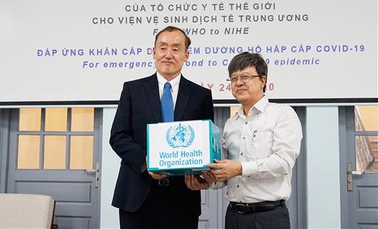 TS. Kidong Park, Trưởng Đại Diện Văn Phòng Tổ chức Y tế Thế giới tại Việt Nam, bàn giao sinh phẩm xét nghiệm để phát hiện vi rút gây bệnh COVID-19 cho TS. Đặng Đức Anh, Viện Trưởng Viện Vệ Sinh Dịch Tễ Trung Ương (NIHE) tại buổi lễ trao tặng hàng viện trợ. (Ảnh: NIHE).