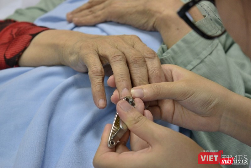 Một nữ điều dưỡng tỉ mẩn cắt móng tay cho bệnh nhân.