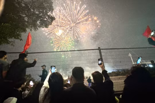 Người dân thích thú dùng điện thoại ghi lại khoảnh khắc pháo phát sáng trên bầu trời. Ảnh: Quỳnh An.