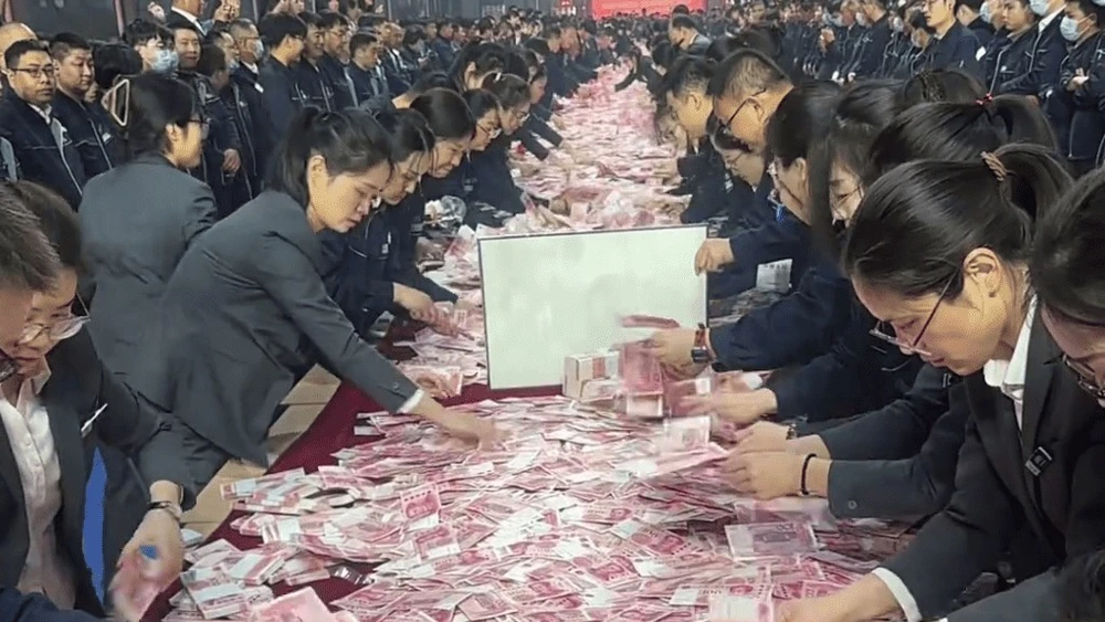 Các nhân viên được thưởng đua nhau đếm tiền để mang về. Ảnh: Singtao.