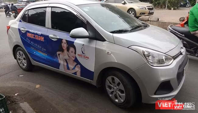 Các taxi công nghệ đều không niêm yết số điện thoại của đơn vị kinh doanh ở hai bên thân xe hoặc hai bên cánh cửa xe. Ảnh: Một xe tuân thủ việc dán logo Grab tại phía trên, bên trái của kính chắn gió nhưng không niêm yết thông tin hãng.