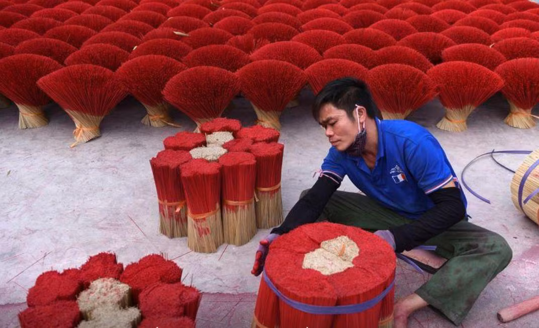 Một công nhân gói nhang khô trong sân ở làng Quảng Phú Cầu (ảnh: Reuters)