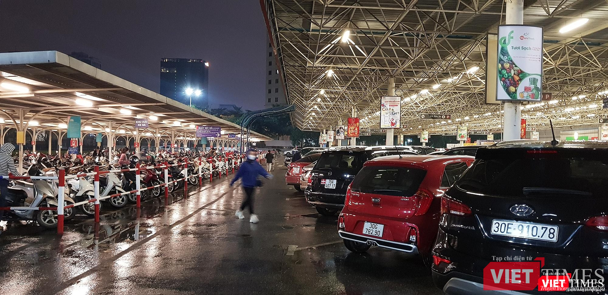 Cả xe máy và xe hơi đỗ kín khoảng sân trước cửa siêu thị. Có thể thấy lượng người đi mua sắm Tết vào chiều tối ngày 28 Tết rất đông đúc