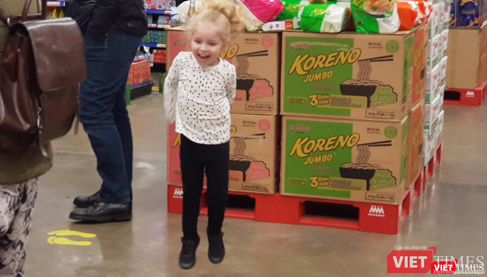 Một bé gái người nước ngoài thích thú chạy nhảy trong siêu thị. Bé gái này thậm chí còn không đeo khẩu trang