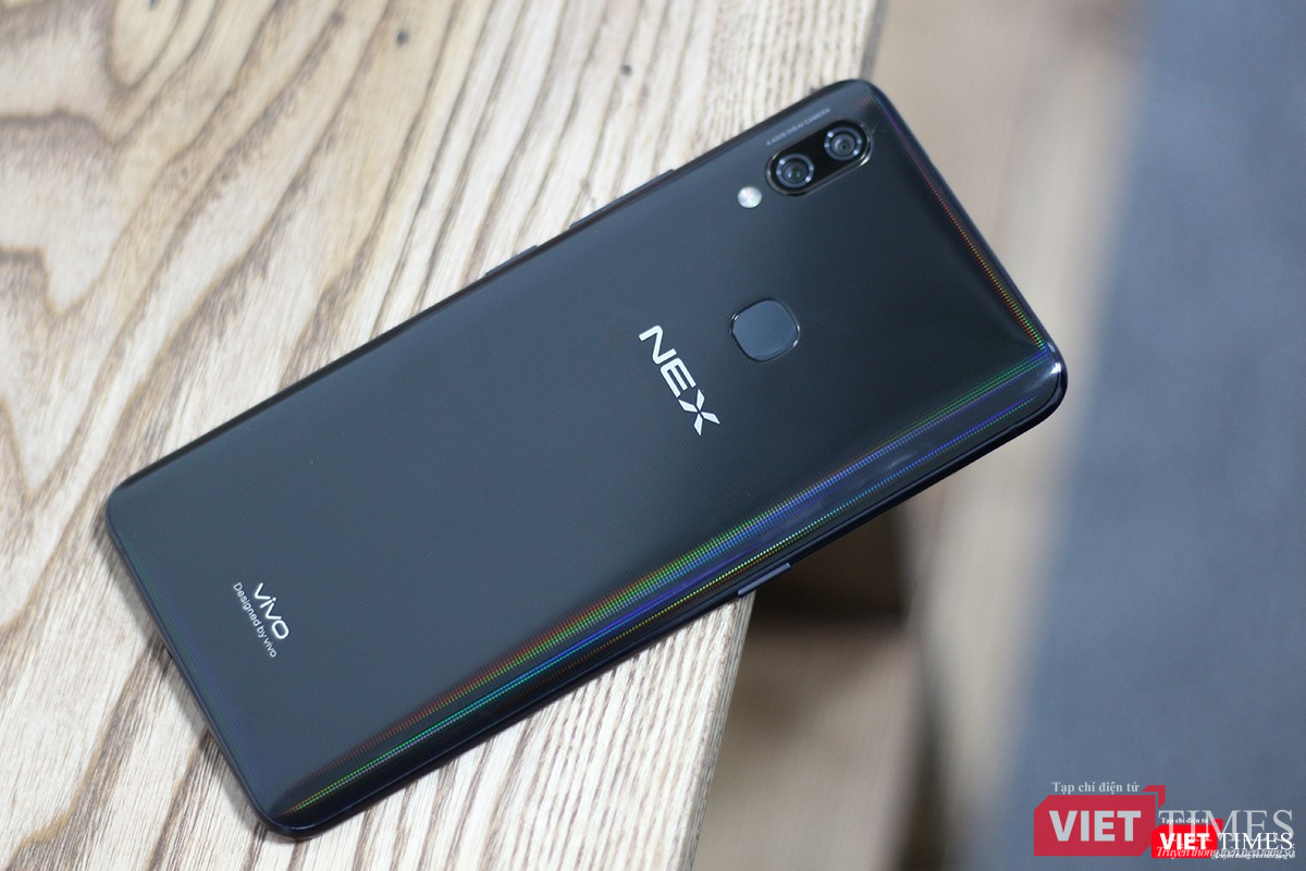 Mặt lưng của Vivo Nex A được làm từ kính, khá bám vân tay. Chúng tôi đã thử dùng khăn lau nhưng vẫn không hết dầu tay. Có lẽ biết vậy nên Vivo đã tặng cho người dùng một ốp lưng "đồng màu đồng chất" trong hộp phụ kiện. Chúng ta có thể thấy sự hiện diện của cụm camera kép và đặc biệt là máy quét vân tay. Ở phiên bản Vivo Nex S cao cấp hơn thì máy quét vân tay được nhúng thẳng vào màn hình, còn bản Nex A này thì nằm ở mặt lưng.