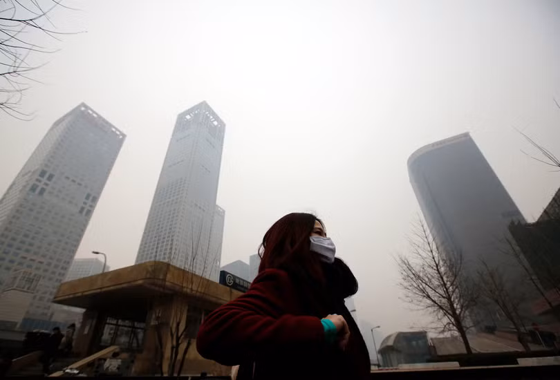 Một người phụ nữ đi qua màn khói bụi ở Bắc Kinh (ảnh: Reuters)