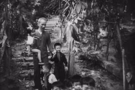 Bác Hồ bế một bé gái và dắt tay cậu bé Hậu năm 1954. Ảnh: NVCC.
