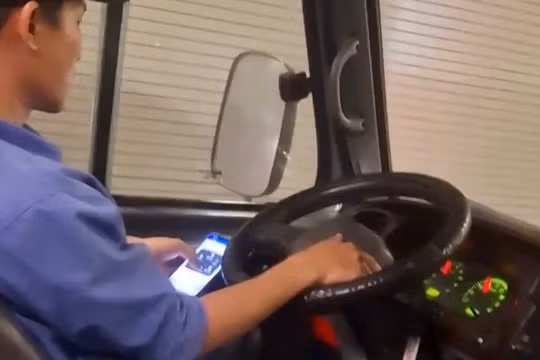 Tài xế vừa lái xe vừa lướt điện thoại. Ảnh cắt từ clip.