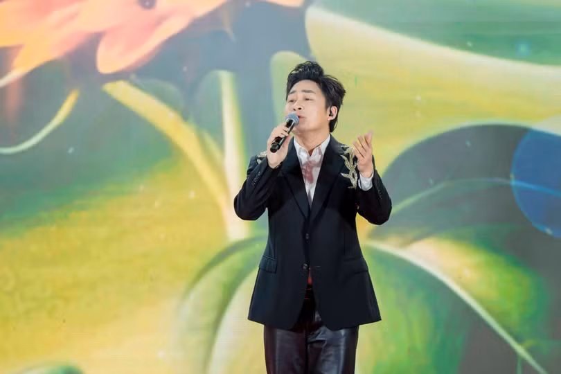 Ca sĩ Tùng Dương biểu diễn trong chương trình nghệ thuật mở màn, với nền hình ảnh tái hiện ký ức đại dịch phía sau sân khấu.