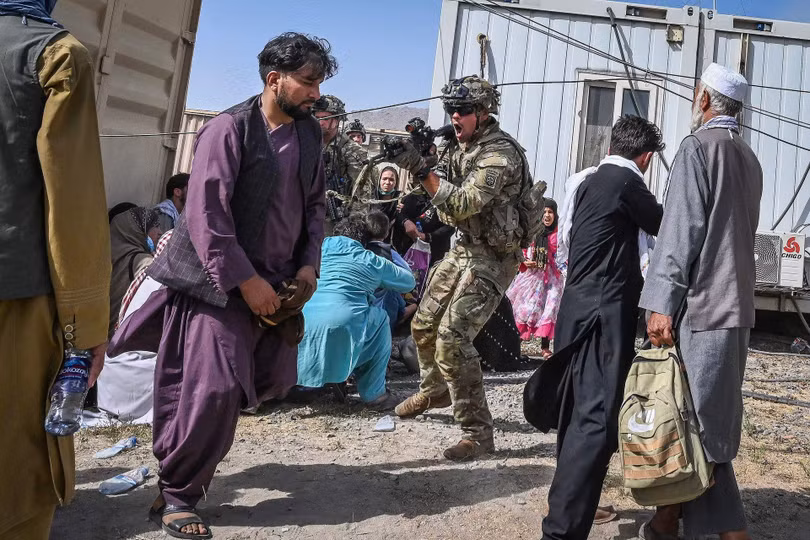 Một lính Mỹ chĩa súng đe dọa những người Afghanistan định vào khu vực cấm (Ảnh: Reuters).
