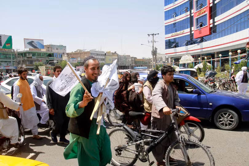 Một người dân Afghanistan mang các lá cờ Taliban bán trên đường phố Kabul (Ảnh: AP).