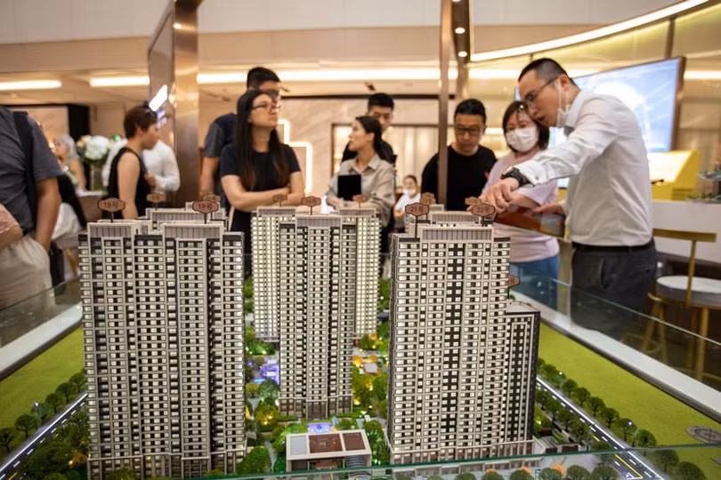 Một nhân viên bán hàng giới thiệu khu chung cư mới cho những người mua tiềm năng tại văn phòng bán hàng ở Thượng Hải.