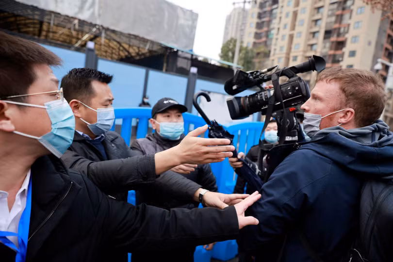 Nhân viên an ninh Trung Quốc ngăn cản các phóng viên tiếp xúc với đoàn chuyên gia WHO (Ảnh: Reuters).