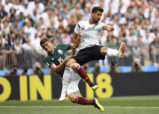 Tiền vệ người Đức Sami Khedira và hậu vệ của Hector Moreno của Mexico ngã sau khi cố gắng đánh đầu. Tiền vệ người Đức Sami Khedira và hậu vệ của Hector Moreno của Mexico ngã sau khi cố gắng đánh đầu.