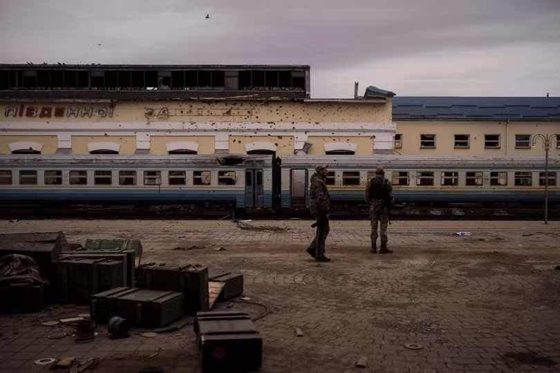 Các binh sĩ Ukraine đứng trước nhà ga xe lửa bị hư hại, trên sân ga còn nhiều đạn dược quân Nga để lại khi rút đi (Ảnh: AP). Các binh sĩ Ukraine đứng trước nhà ga xe lửa bị hư hại, trên sân ga còn nhiều đạn dược quân Nga để lại khi rút đi (Ảnh: AP).