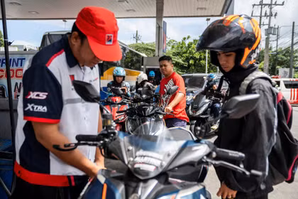 Các tài xế xe máy xếp hàng chờ trong khi một nhân viên đang đổ xăng cho xe máy tại một trạm xăng ở thành phố Quezon, khu vực đô thị Manila, Philippines ngày 9/3. Ảnh: Reuters.