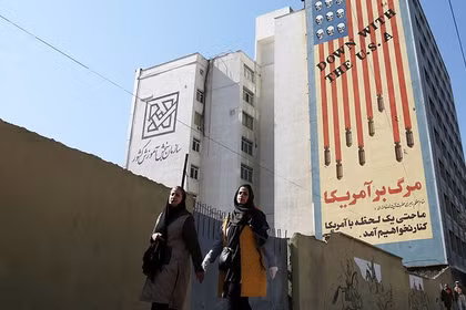 Hai phụ nữ đi qua một biểu ngữ nội dung chống Mỹ ở Tehran, Iran. Ảnh: Getty.
