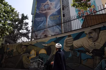 Một giáo sĩ Iran đi bộ bên cạnh một bảng quảng cáo chống Israel trên một tòa nhà ở Tehran, Iran, ngày 9/6. Ảnh: Ảnh: Reuters.