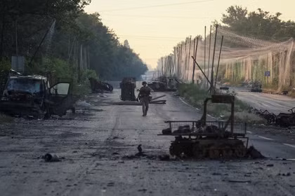 Một binh sĩ thuộc Lữ đoàn hợp nhất "Khyzhak" của Cảnh sát tuần tra Ukraine đi dọc theo một con đường gần lưới chống UAV và các phương tiện quân sự bị phá hủy khi tham gia nhiệm vụ bảo vệ một con đường khỏi UAV của Nga giữa các thị trấn tiền tuyến Druzhkivka và Kostiantynivka, ngày 24/6. Ảnh: Reuters.