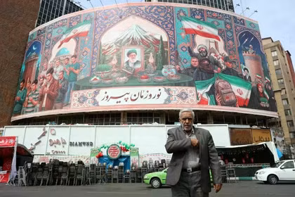 Người dân Iran đi ngang qua một bảng quảng cáo tại quảng trường Valiasr ở Tehran, Iran ngày 22/3. Ảnh: EPA.