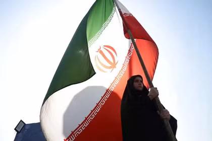 Một người phụ nữ cầm cờ Iran trên đường phố Tehran, Iran, ngày 10/6. Ảnh: Reuters.