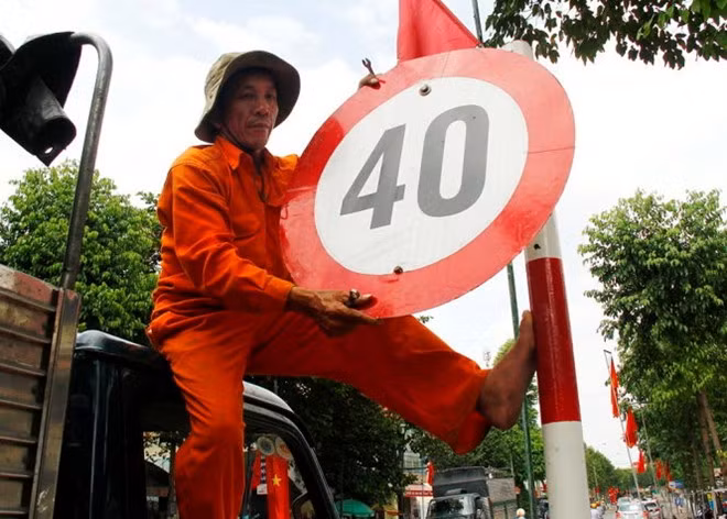 Công nhân Công ty Công trình Đô thị Bình Dương tháo dỡ biển hạn chế tốc độ 40km/h tại đường Thích Quảng Đức, TP Thủ Dầu Một chiều 28/1. 