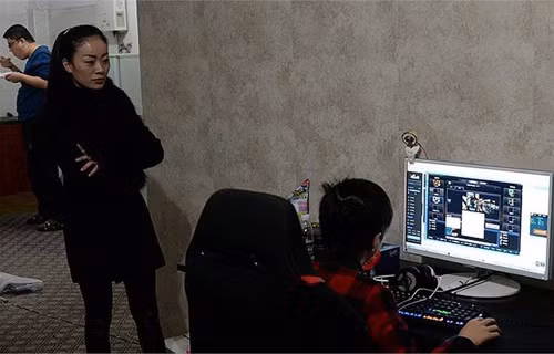 Mẹ của Tiểu Tânđang đứng xem con mình phát sóng trực tiếp buổi chơi game. Ảnh:Nownews.