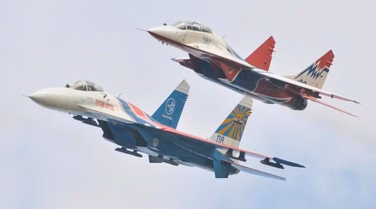Tiêm kích MiG-29 (bên trên) đang bay cùng tiêm kích Su-27 (Ảnh: Military Watch Magazine)