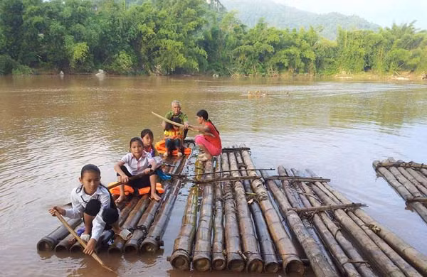 Chị Vi Thị Thu (xã Bình Trung, Cao Lộc, Lạng Sơn) đưa con ra bè để sang sông đến khai giảng. Ảnh:Hồng Vân.