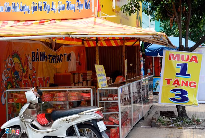 Treo bảng giảm giá mua 1 tặng 3 nhưng quầy bánh trung thu bên vòng xoay Âu Cơ - Lê Đại Hành vẫn vắng bóng khách. Nhân viên ngồi chơi bên trong quầy.