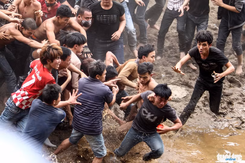 Một thanh niên cầm được quả phết cố gắng thoát khỏi đám đông và rơi vào vũng nước - Ảnh: Nguyễn Khánh