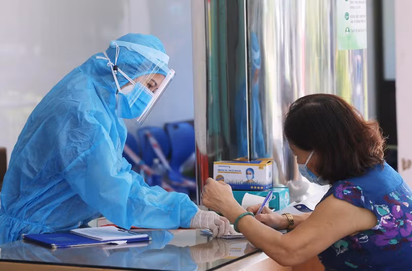 Nhân viên y tế hướng dẫn người dân khai báo y tế (Ảnh: Lê Bảo - Minh Thùy) 