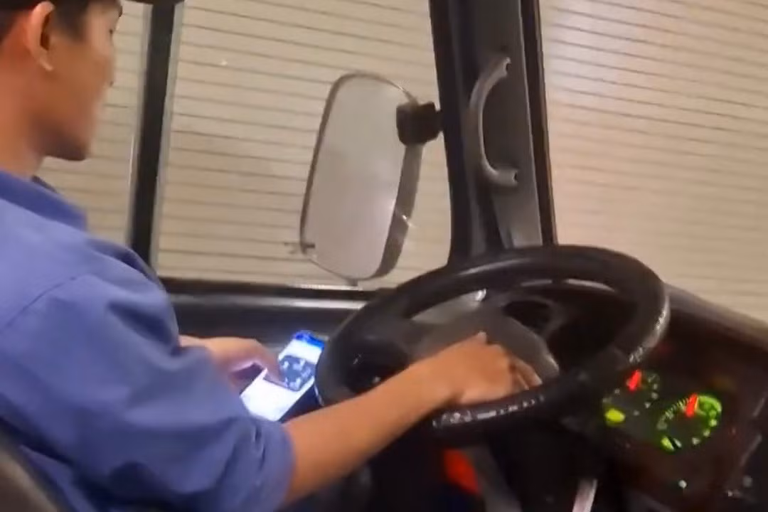 Tài xế vừa lái xe vừa lướt điện thoại. Ảnh cắt từ clip.